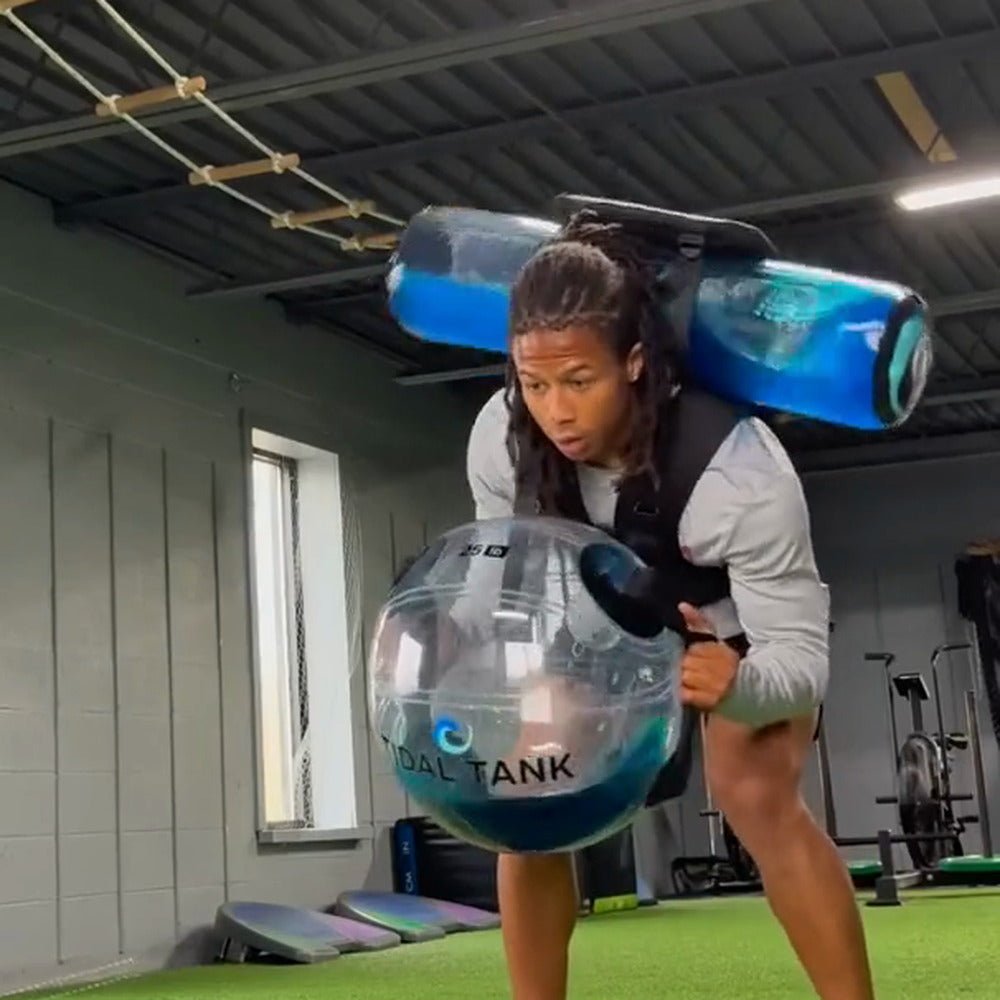 Lateral agility work in a gym with a water-filled tube across the shoulders
