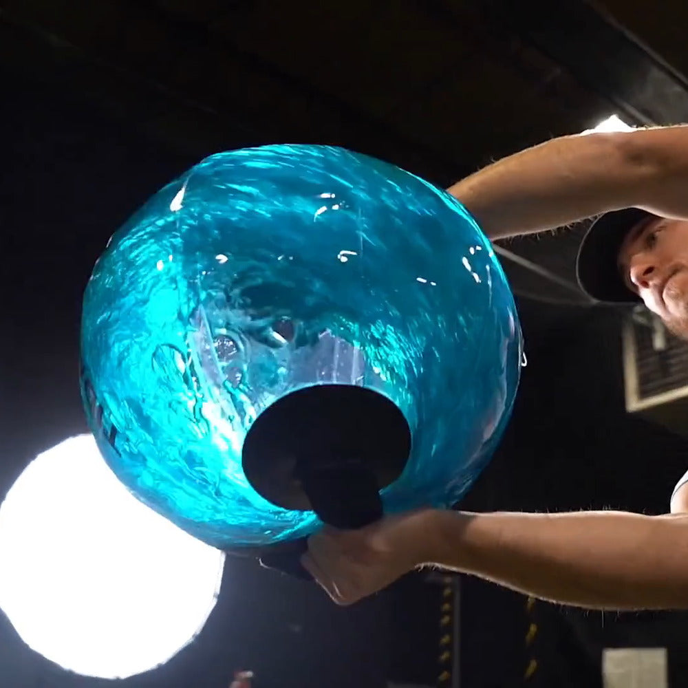 A water-filled sphere held overhead, the moving water lit from behind