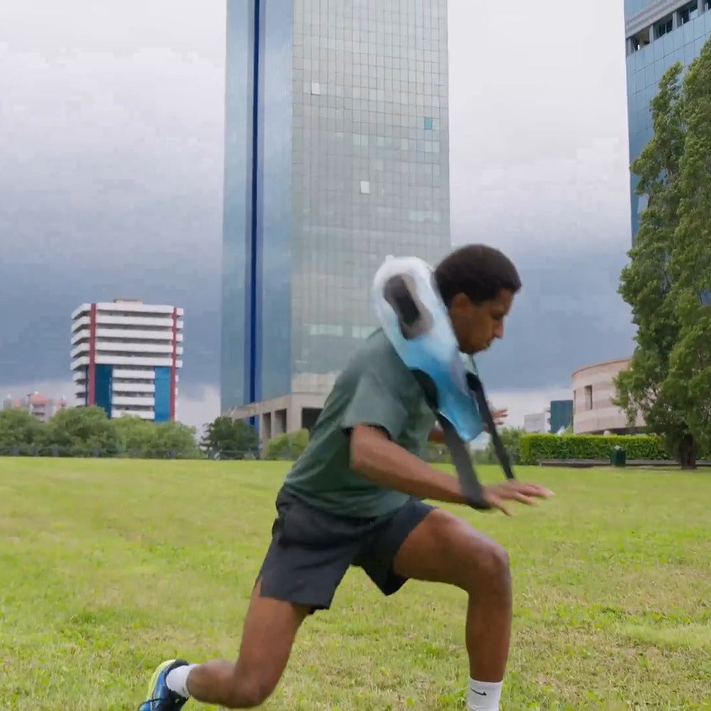 A runner training outdoors with a water-filled tube across the shoulders