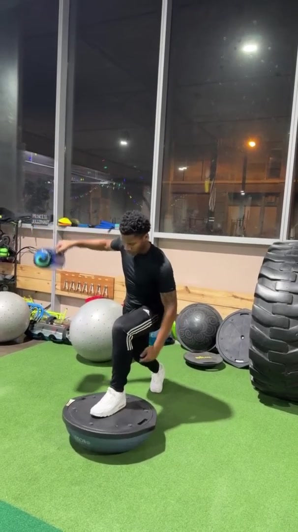An athlete balancing on one leg while holding a water-filled kettle.