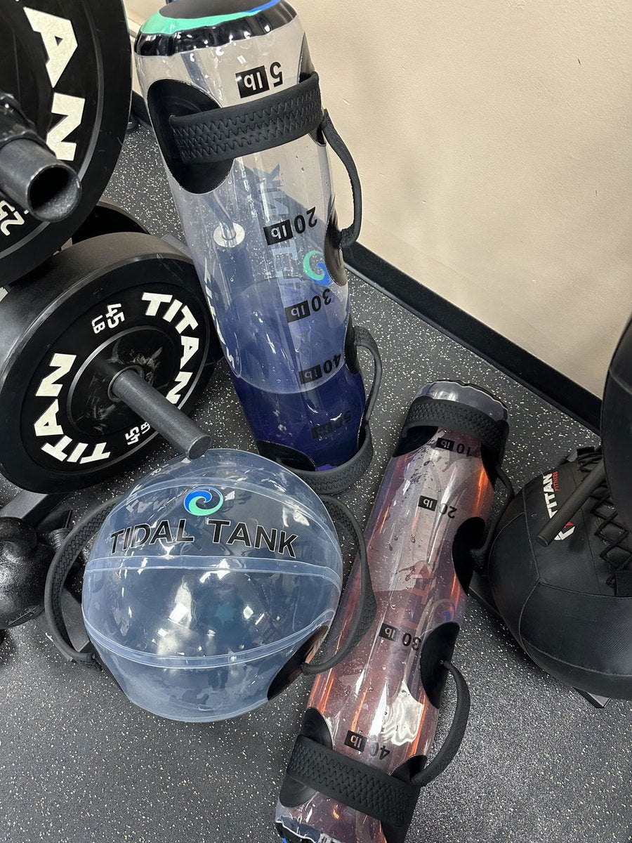 A water-filled tube and sphere on the floor beside a loaded barbell and plates.