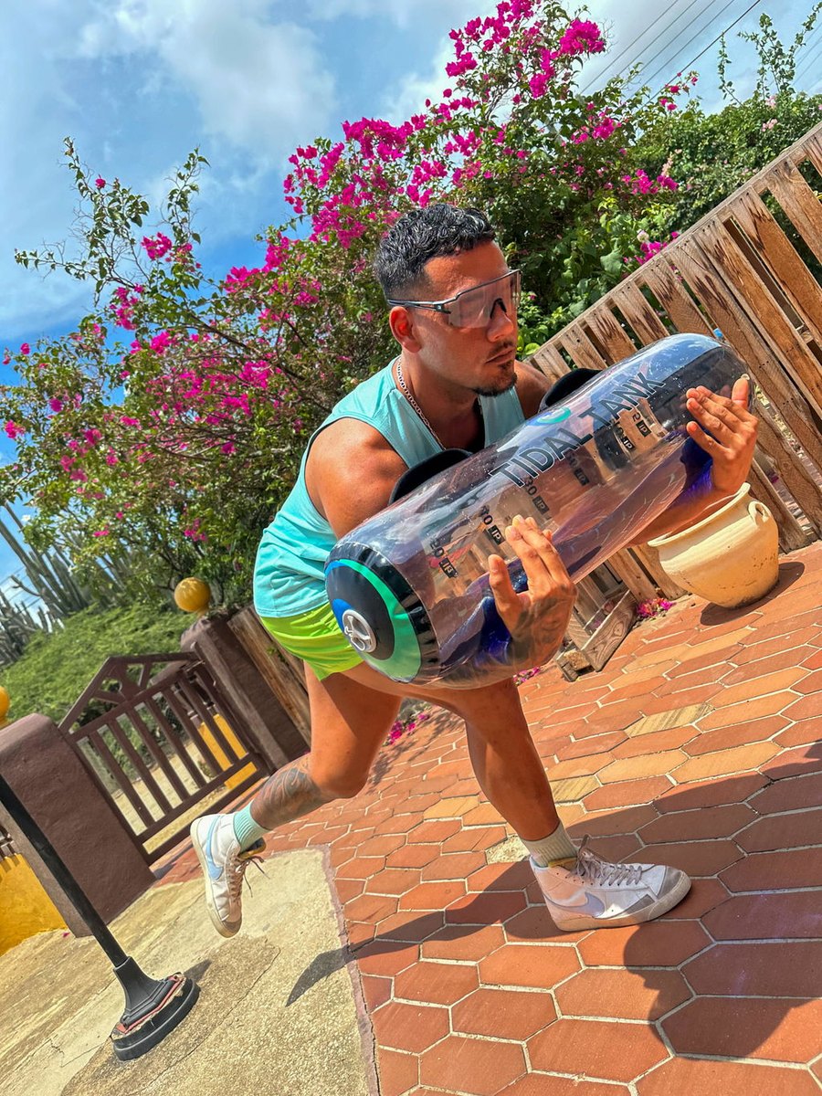 Someone carrying a water-filled tube across a garden patio.