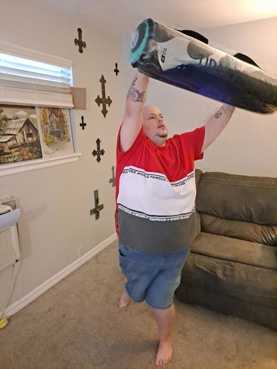 An older man pressing a water-filled tube overhead in his living room.