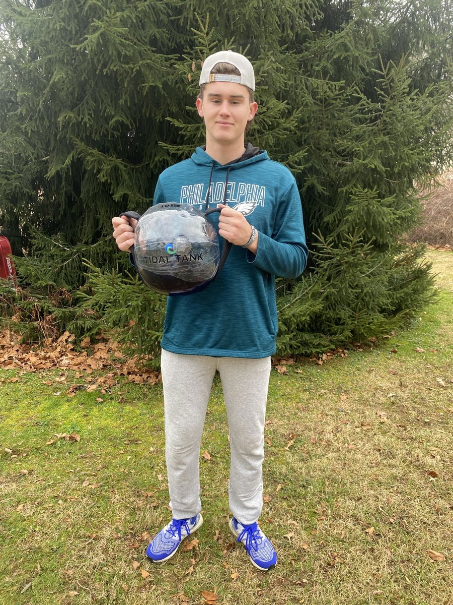 Someone holding a water-filled sphere outdoors in front of pines.