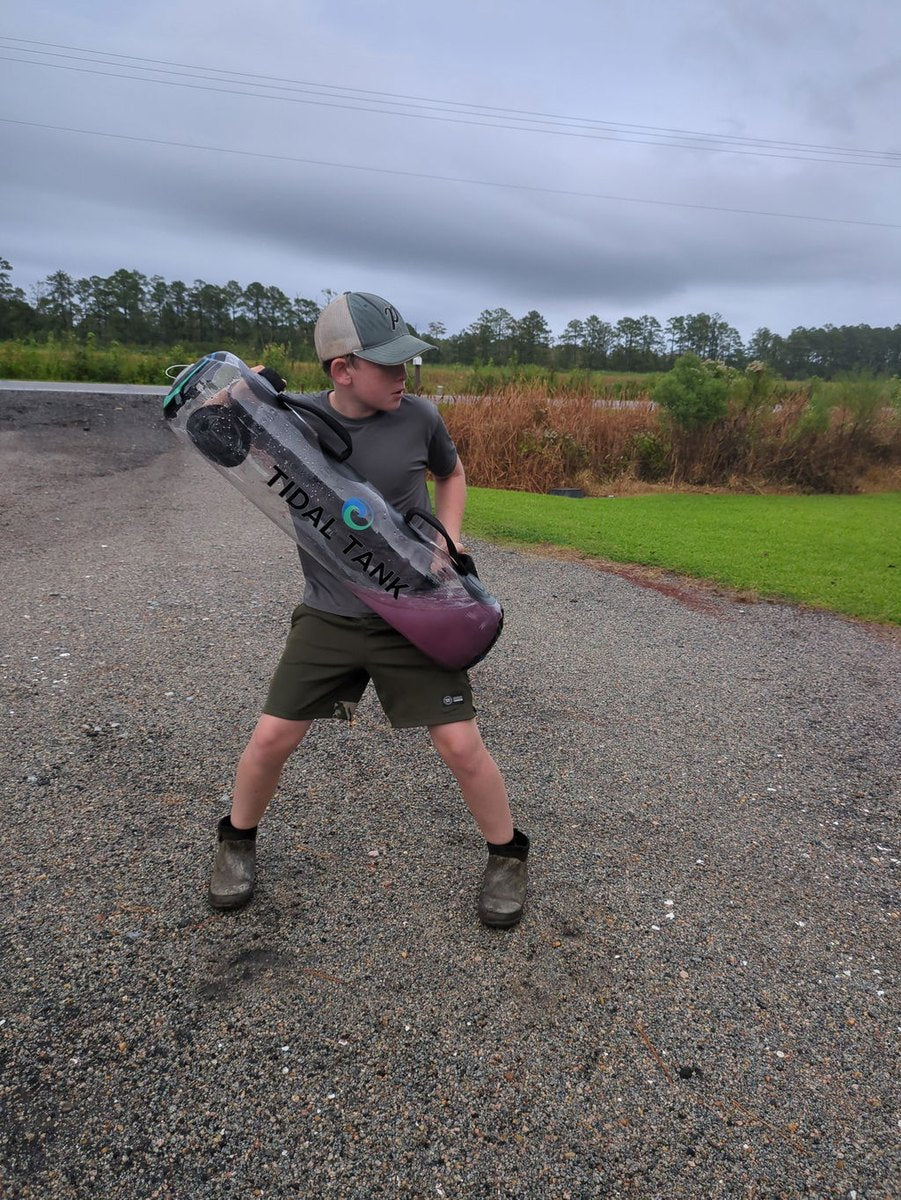 Someone swinging a water-filled tube on an open gravel road.