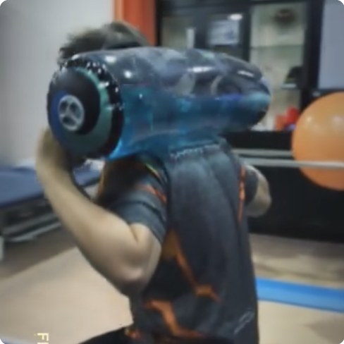 A water-filled tube racked on one shoulder in a dark gym.