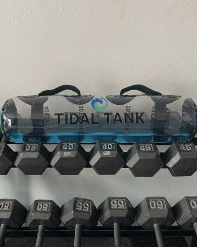 A water-filled tube standing in front of a rack of dumbbells.