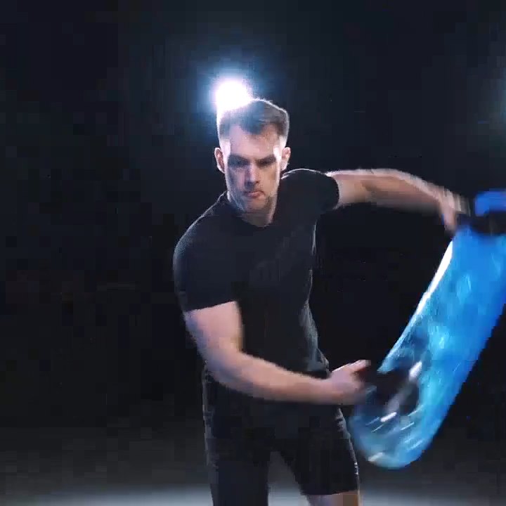 Athlete rotating a water-filled HydroFit tube under studio light.